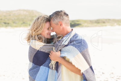 Happy couple wrapped up in blanket