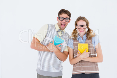 geeky hipster couple holding books and smiling at camera