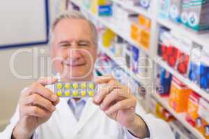 Senior pharmacist holding up blister packs
