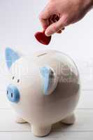 Hand putting heart in piggy bank