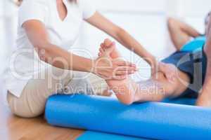 Trainer working with man on exercise mat