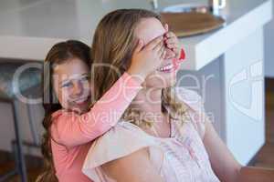Happy little girl covering her mother eyes