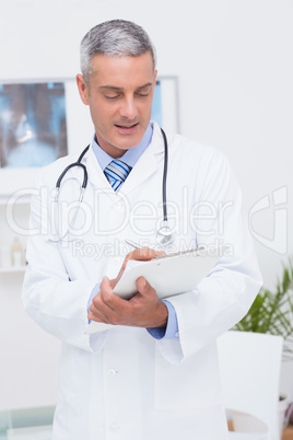 Happy doctor writing on clipboard