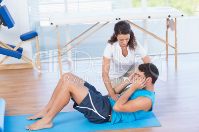 Trainer working with man on exercise mat