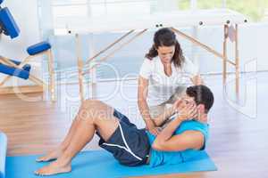 Trainer working with man on exercise mat