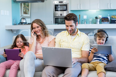 Happy family on the couch together using devices