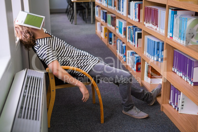 Student asleep in the library with book on his face