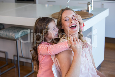 Happy little girl covering her mother eyes