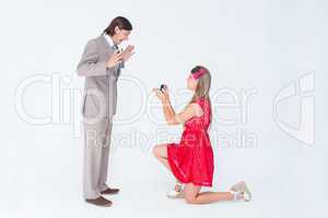 Pretty hipster on bended knee doing a marriage proposal to her b