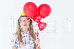 Geeky hipster smiling at camera and holding red balloons
