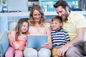 Happy family on the couch together using tablet