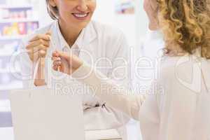 Pharmacist and costumer holding paper bag