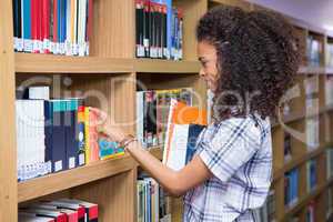 Student picking a book from shelf in library