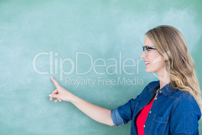 Smiling geeky teacher pointing the blackboard