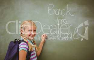 Portrait of cute little girl writing on blackboard