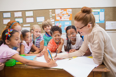 Teacher and pupils working at desk together