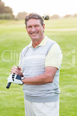 Golfer standing and swinging his club smiling at camera