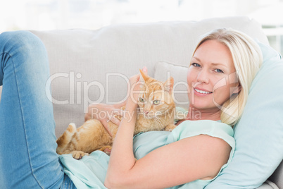Woman embracing cat while lying on sofa