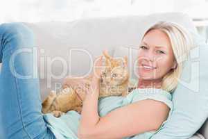 Woman embracing cat while lying on sofa