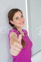 Casual young woman gesturing thumbs up