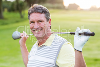 Golfer standing and swinging his club smiling at camera