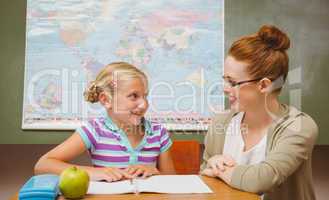 Teacher assisting girl with homework in classroom