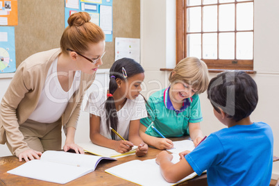 Teacher and pupils working at desk together