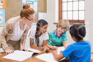 Teacher and pupils working at desk together