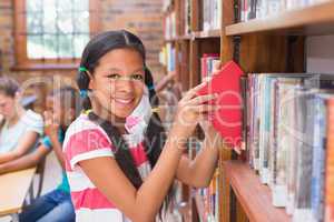 Cute pupil looking for books in library