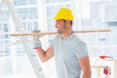 Handyman carrying planks in building