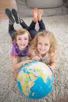 Brother and sister with globe lying on rug