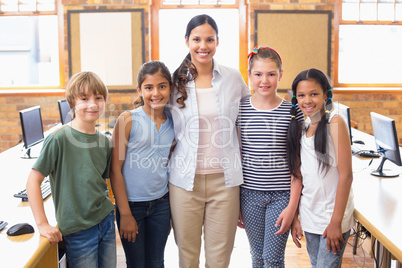 Cute pupils and teacher smiling at camera in computer class