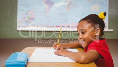 Cute little girl writing book in classroom