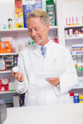Smiling senior pharmacist holding prescription and jar