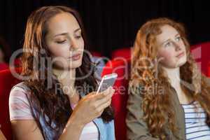 Woman text messaging on her mobile during movie