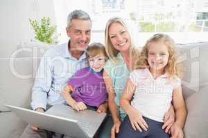 Parents and children with laptop sitting on sofa