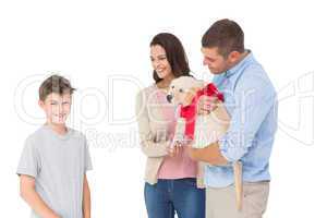 Parents gifting puppy to boy against white background