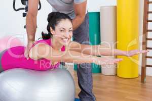 Trainer with smiling woman on exercise ball