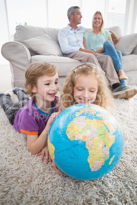 Children exploring globe while parents sitting on sofa