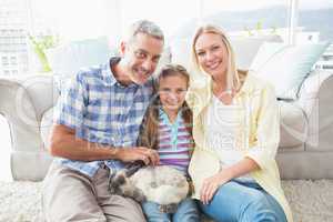 Happy parents and daughter with rabbit in living room