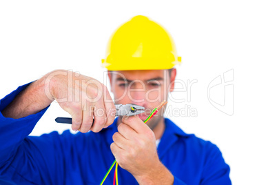 Electrician wearing hard hat while cutting wire with pliers