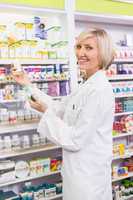 Smiling pharmacist holding boxes of medicine