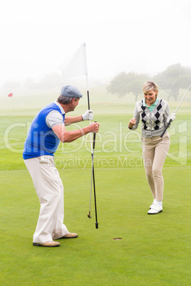 Golfing couple cheering on the putting green