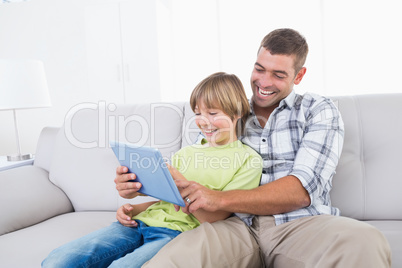 Father and son playing game on digital tablet