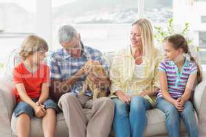 Family sitting with cat on sofa at home