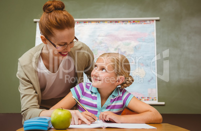 Teacher assisting girl with homework in classroom