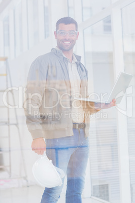 Confident architect with hardhat and laptop in office