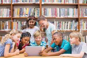 Cute pupils using tablet computer in library