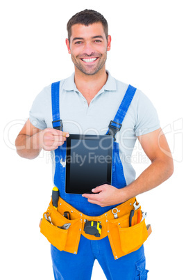 Happy repairman in overalls holding digital tablet