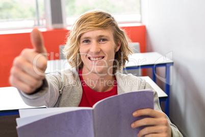 Male student gesturing thumbs up in classroom